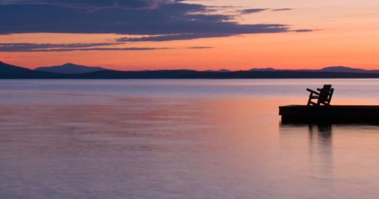 Adirondack chair at the end of a quiet pier overlooking calm water at sunset, symbolizing peace and reflection in the final days of life.